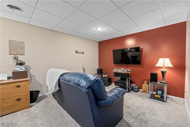 carpeted living room with a drop ceiling and baseboards