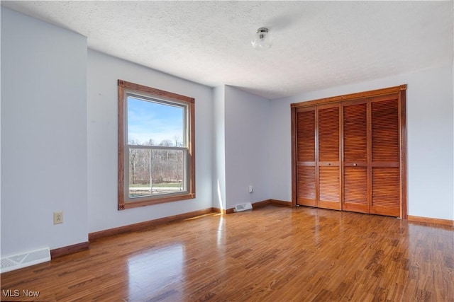 3871 Foskett Rd, Medina, OH 44256 - unfurnished bedroom with a closet, a textured ceiling, visible vents, baseboards, and wood finished floors