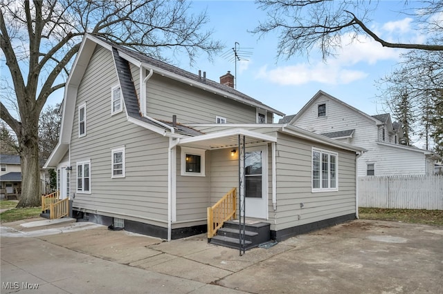 back of house with a chimney, entry steps, fence, and a patio