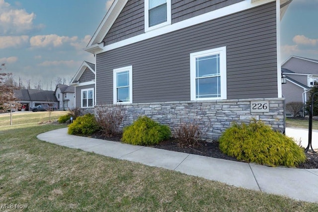 view of property exterior with stone siding and a lawn