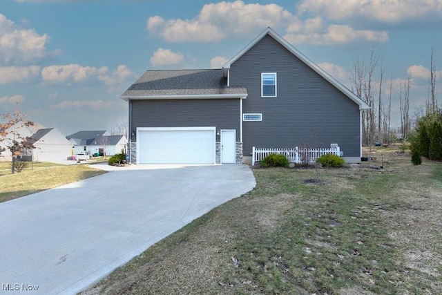 view of side of home with concrete driveway, a garage, and a lawn