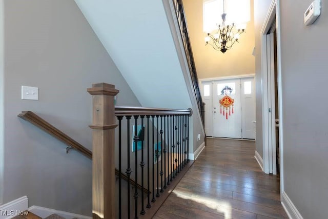 hall featuring a chandelier, hardwood / wood-style floors, an upstairs landing, and baseboards