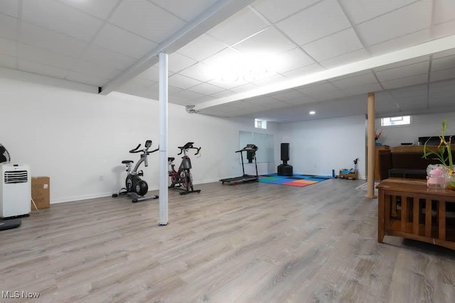 exercise area with light wood-style floors, baseboards, and a paneled ceiling