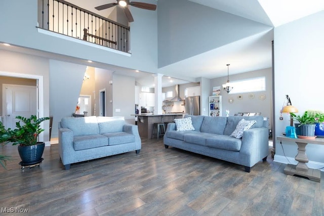 living room with ceiling fan, dark wood finished floors, baseboards, and a towering ceiling