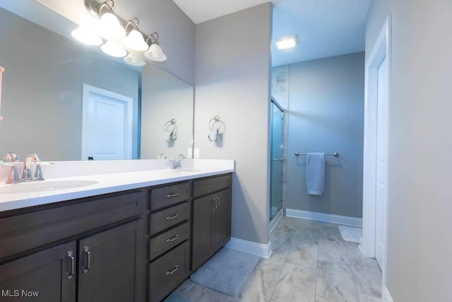 bathroom featuring a stall shower, a chandelier, double vanity, and baseboards
