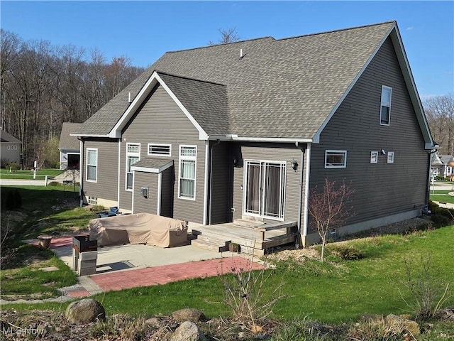 rear view of property featuring a patio, a shingled roof, and a yard