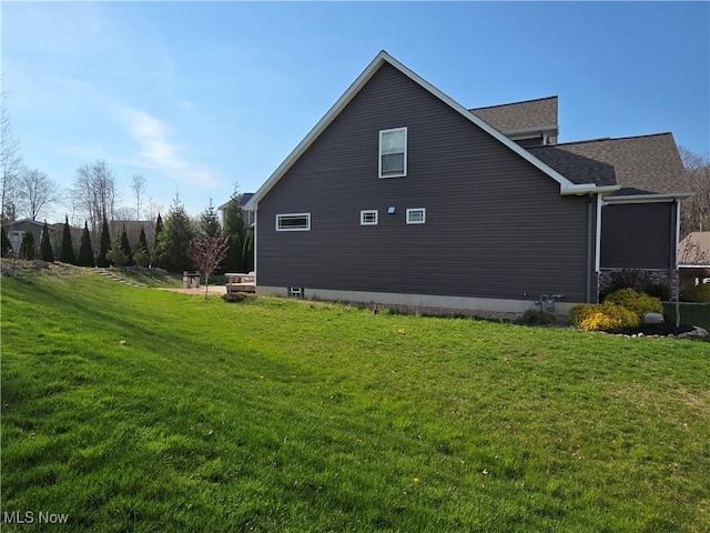 view of side of home featuring a yard and roof with shingles