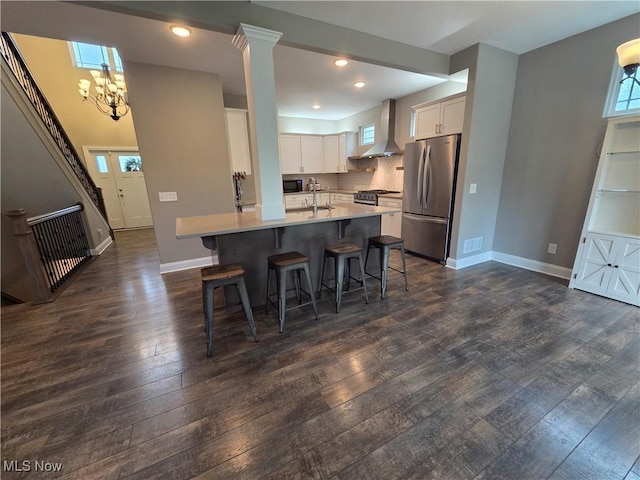 226 Hidden Glen Trl, Chardon, OH 44024 - kitchen featuring appliances with stainless steel finishes, wall chimney range hood, dark wood finished floors, a kitchen bar, and white cabinetry