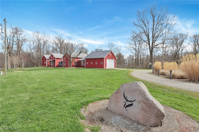 view of yard featuring gravel driveway, an outdoor structure, and a detached garage