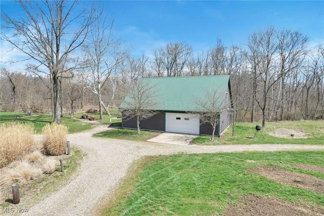view of home's exterior featuring a lawn, an outdoor structure, driveway, and metal roof