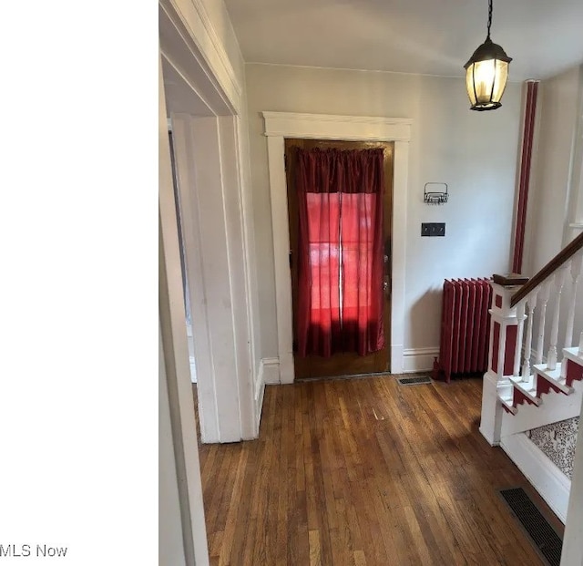 entryway featuring radiator heating unit, visible vents, wood finished floors, stairs, and baseboards