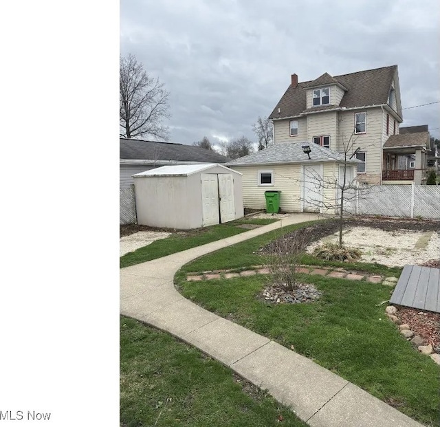 view of yard featuring a storage shed, an outdoor structure, and fence