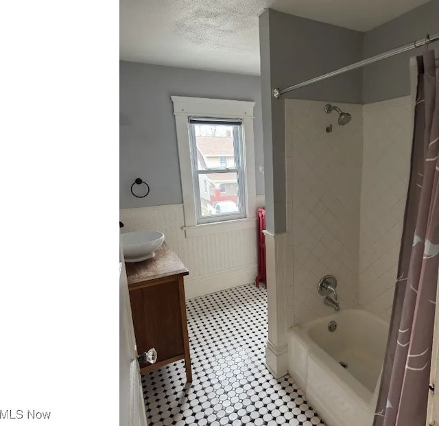 bathroom with vanity, tile patterned floors, shower / bath combination with curtain, a textured ceiling, and wainscoting