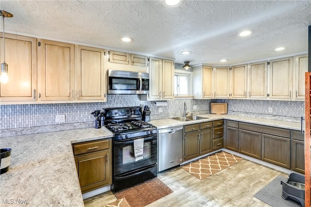 kitchen with light countertops, stainless steel appliances, decorative backsplash, a sink, and light wood-style floors