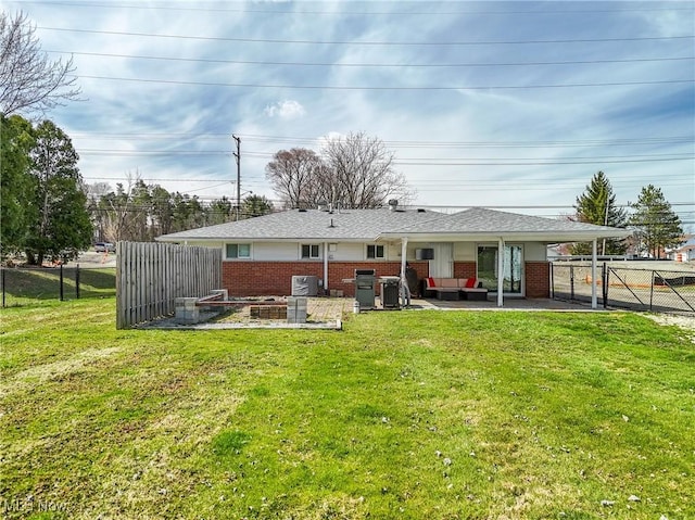 rear view of property featuring a lawn, brick siding, a fenced backyard, and a patio
