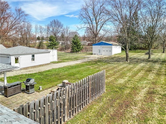 view of yard featuring an outbuilding, driveway, fence, and a detached garage
