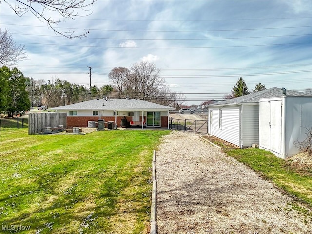 exterior space featuring an outdoor structure, fence, brick siding, a yard, and a patio area