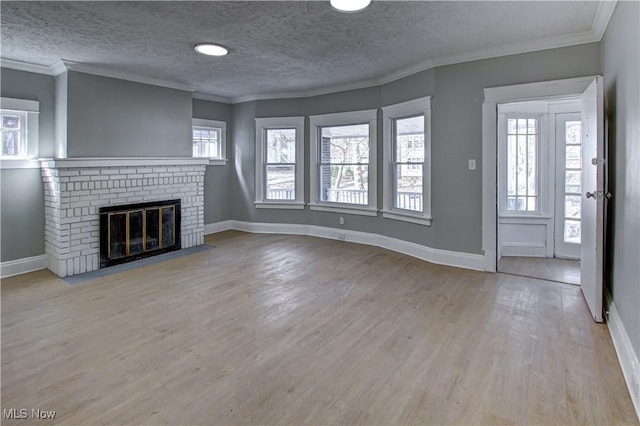 unfurnished living room with baseboards, crown molding, wood finished floors, and a brick fireplace