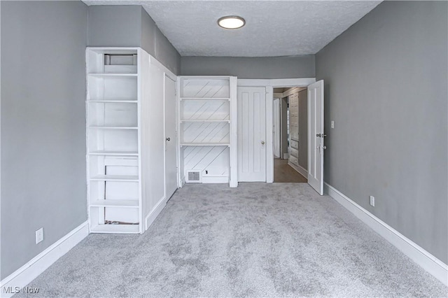 unfurnished bedroom with baseboards, visible vents, carpet, and a textured ceiling