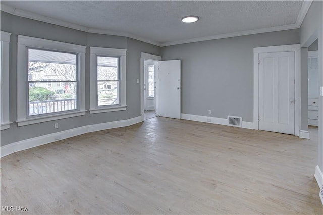 spare room featuring visible vents, wood finished floors, ornamental molding, and a textured ceiling