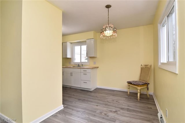 210 Magnolia Ave, Northfield, OH 44067 - unfurnished dining area featuring an inviting chandelier, light wood-style flooring, a sink, and baseboards