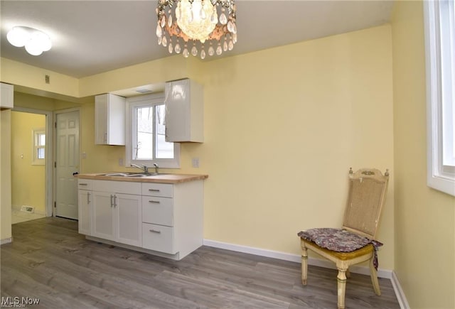 210 Magnolia Ave, Northfield, OH 44067 - kitchen with dark wood-style floors, white cabinetry, a sink, and an inviting chandelier