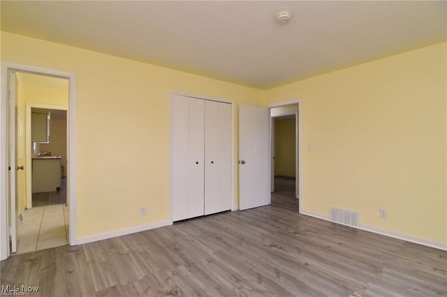 210 Magnolia Ave, Northfield, OH 44067 - unfurnished bedroom featuring a closet, wood finished floors, ensuite bathroom, baseboards, and visible vents