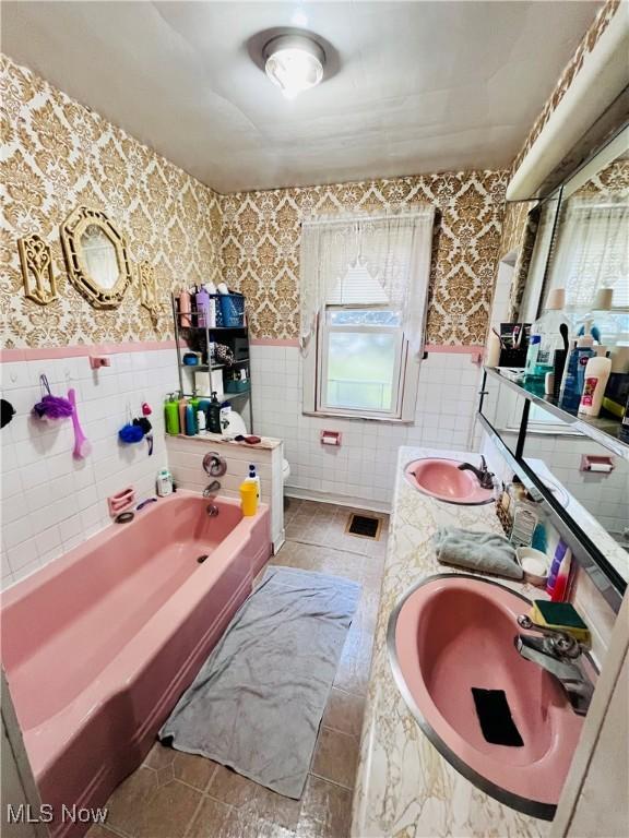 319 Grant St, Newell, WV 26050 - full bathroom with tile walls, wallpapered walls, wainscoting, a garden tub, and double vanity