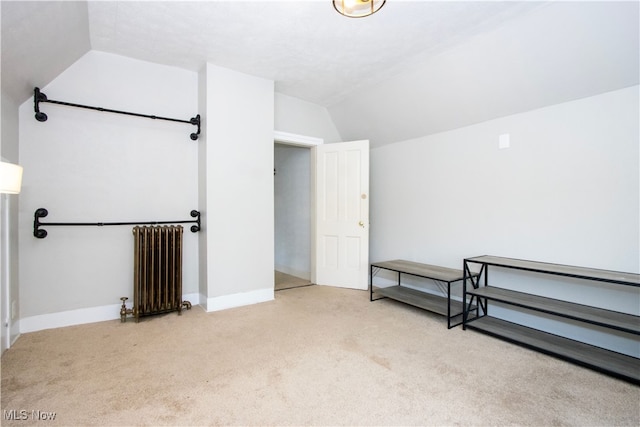 interior space featuring radiator heating unit, carpet floors, baseboards, and vaulted ceiling