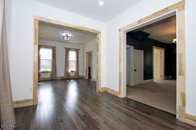 spare room with baseboards and dark wood-style flooring