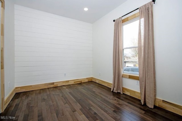 unfurnished room with dark wood-style flooring and baseboards