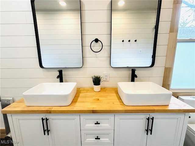 full bath featuring double vanity, a sink, and recessed lighting