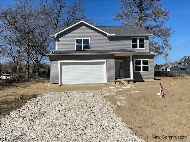 traditional-style house with an attached garage, driveway, and fence