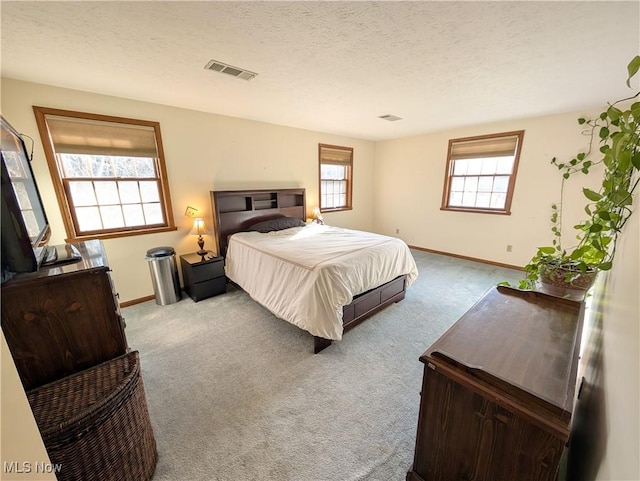 bedroom with baseboards, carpet flooring, a textured ceiling, and visible vents