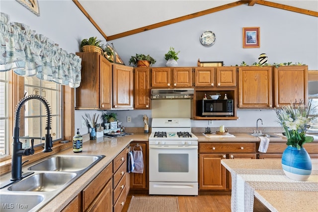 1122 Lake Rd, Conneaut, OH 44030 - kitchen featuring under cabinet range hood, white gas stove, a sink, and vaulted ceiling