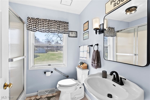 1122 Lake Rd, Conneaut, OH 44030 - bathroom featuring visible vents, baseboards, toilet, a shower with door, and a sink