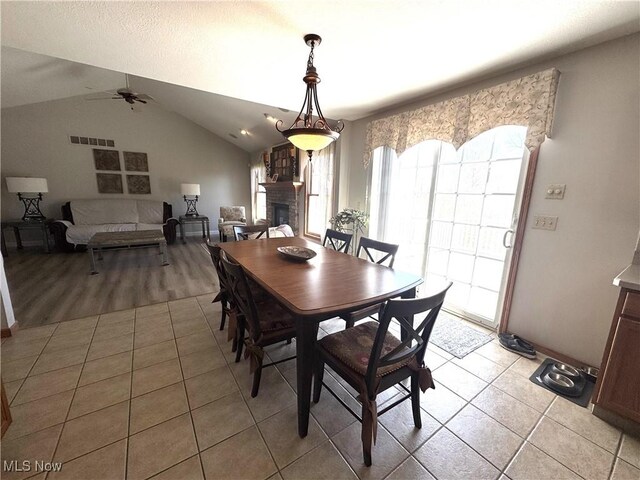 33 Mallards Xing, Canfield, OH 44406 - dining room with vaulted ceiling, a large fireplace, light tile patterned flooring, visible vents, and a ceiling fan