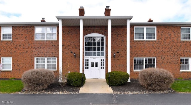 view of front facade featuring brick siding and a chimney