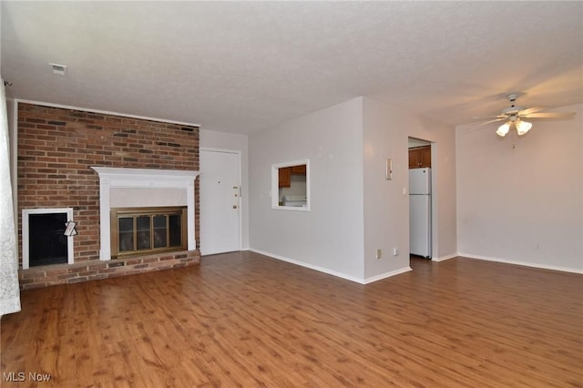 unfurnished living room featuring a textured ceiling, a fireplace, wood finished floors, and a ceiling fan