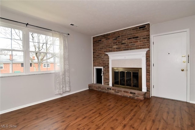 unfurnished living room featuring baseboards, a fireplace, visible vents, and wood finished floors
