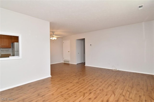 unfurnished room with baseboards, visible vents, light wood-style floors, and ceiling fan