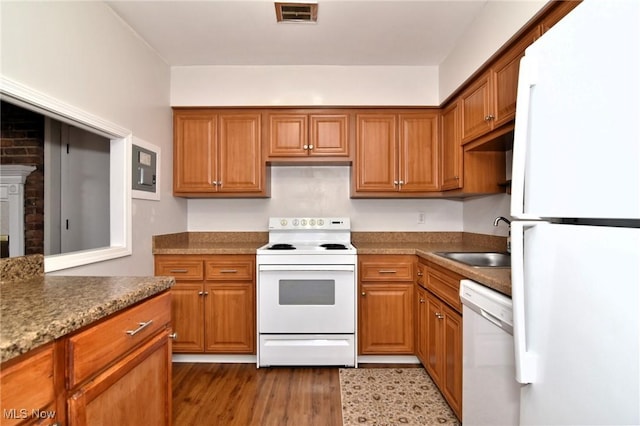 kitchen with visible vents, a sink, brown cabinetry, and white appliances