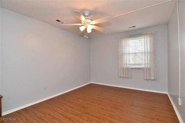 empty room with a ceiling fan, wood finished floors, baseboards, and visible vents