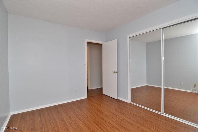 unfurnished bedroom featuring baseboards, a closet, and wood finished floors