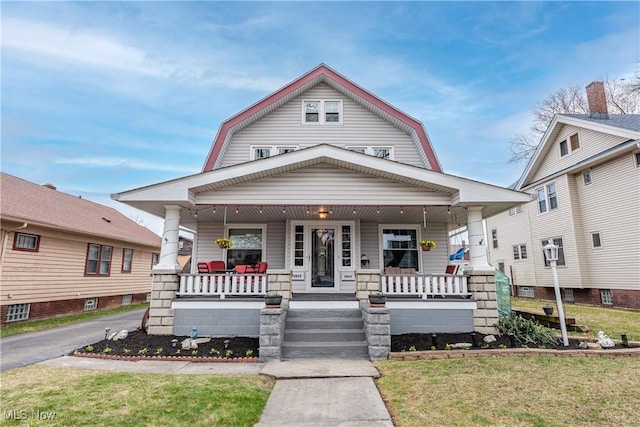 dutch colonial featuring a gambrel roof, a front yard, and a porch
