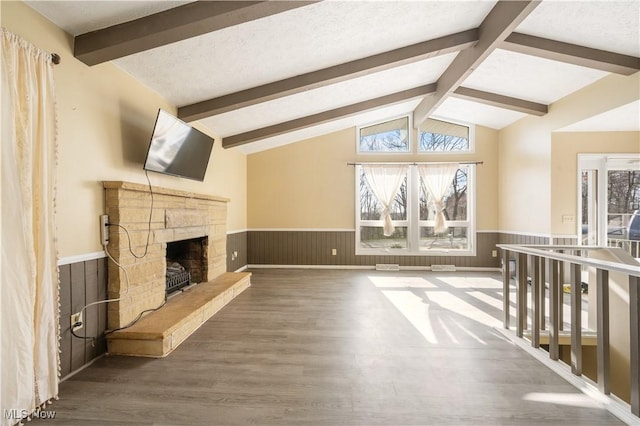 70 Iroquois Trl, Malvern, OH 44644 - unfurnished living room featuring a wainscoted wall, vaulted ceiling with beams, wood finished floors, a textured ceiling, and a stone fireplace