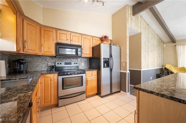 70 Iroquois Trl, Malvern, OH 44644 - kitchen featuring lofted ceiling with beams, wainscoting, appliances with stainless steel finishes, dark stone countertops, and light tile patterned floors