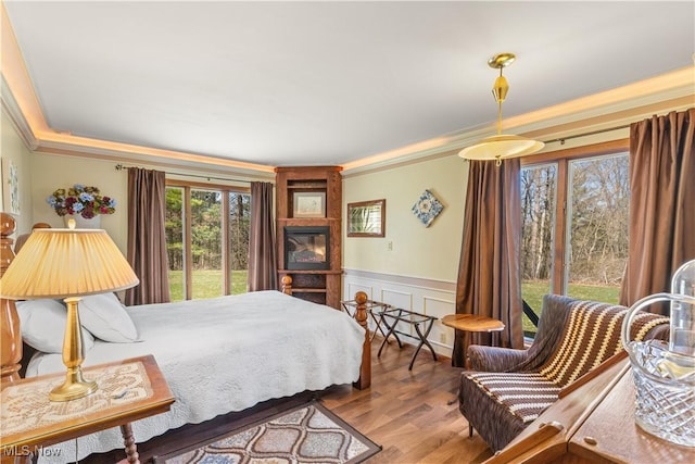 bedroom with a decorative wall, a wainscoted wall, ornamental molding, and wood finished floors