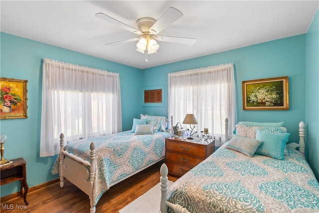 bedroom with a ceiling fan, multiple windows, and wood finished floors
