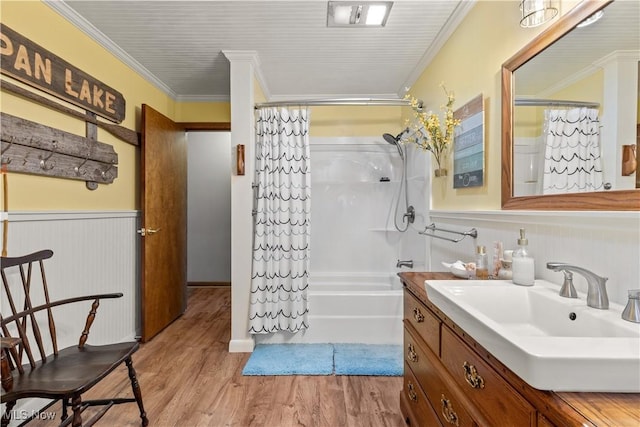 full bath featuring a wainscoted wall, vanity, ornamental molding, and wood finished floors